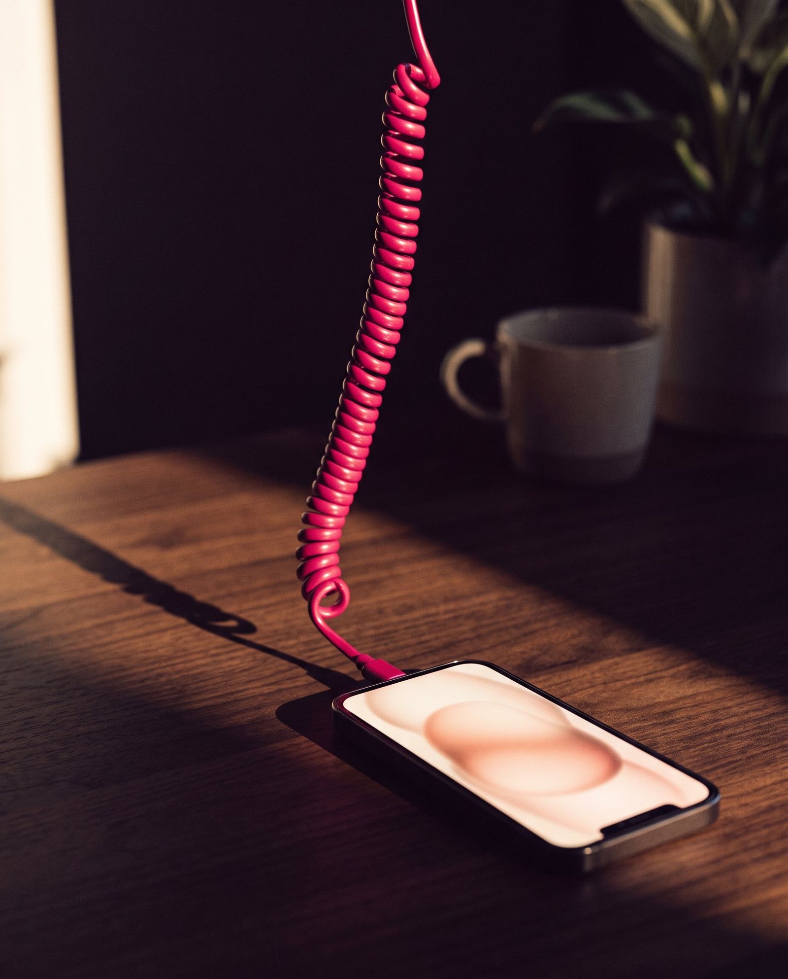 Móvil sobre una mesa de madera con un cable en espiral fucsia
